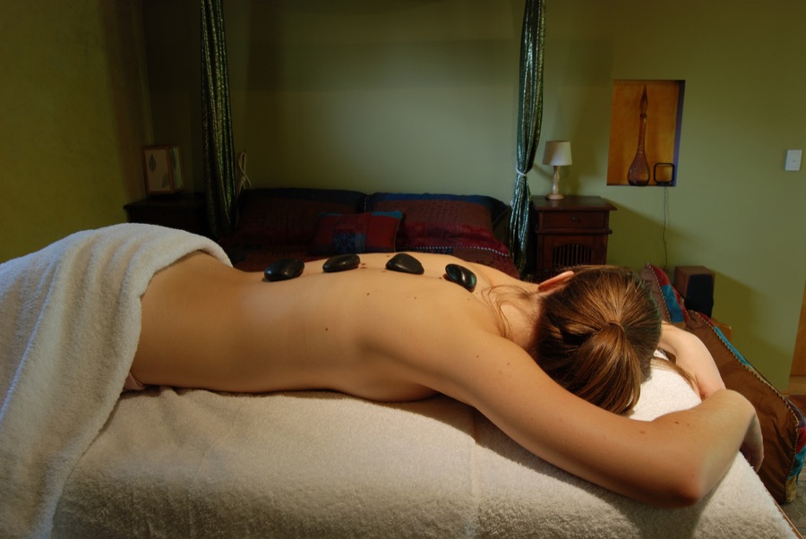 Smooth heated basalt stones resting along a back during a hot stone massage